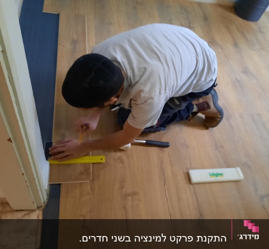 אדם מתקין פרקט בעזרת סרגל ועיפרון